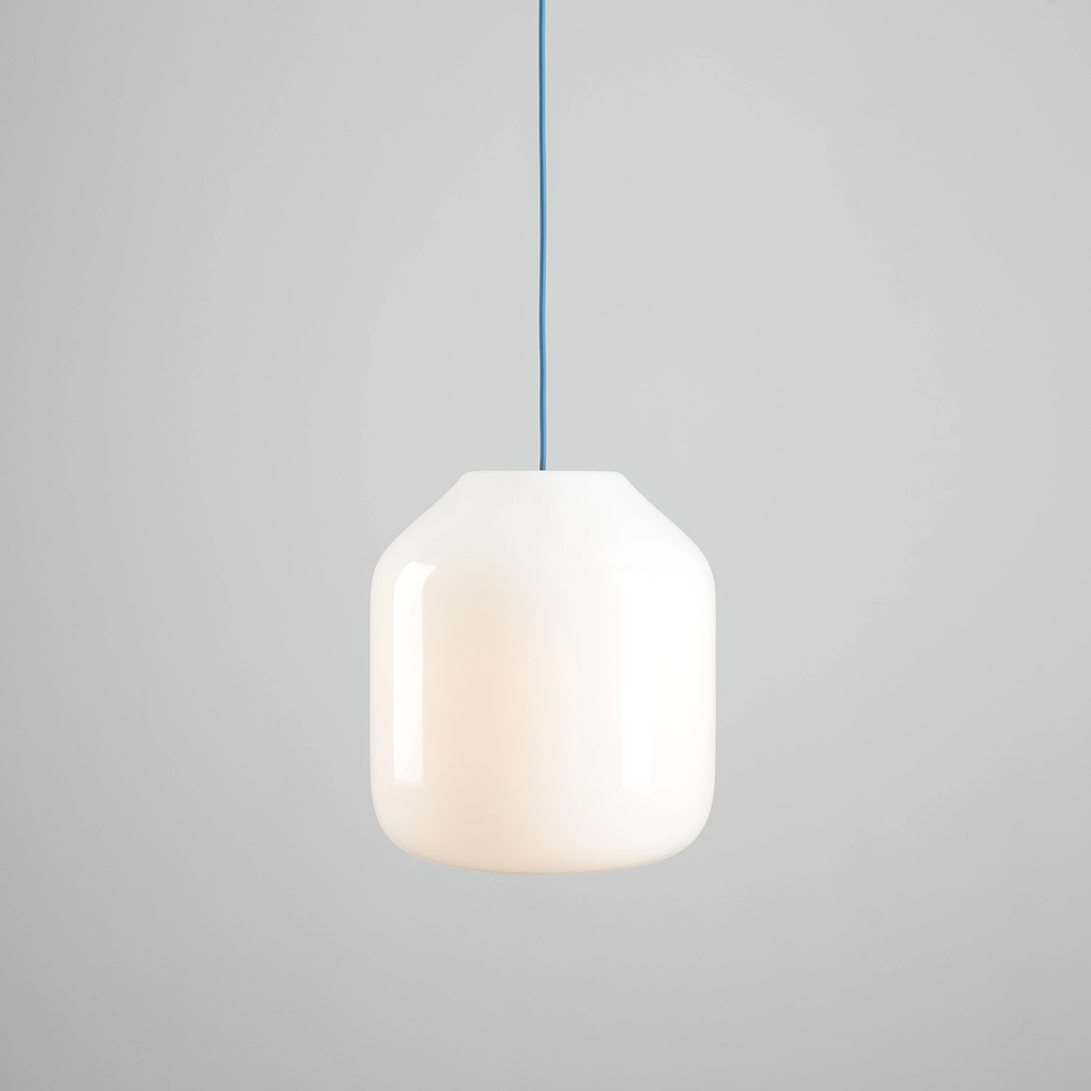 Lampa wisząca Flask Sapphire D27 w kolorze białym z niebieskim kablem, o kształcie cylindrycznym, wykonana z materiału transparentnego. Zawieszona na prostym, długim przewodzie, idealna do nowoczesnych wnętrz.