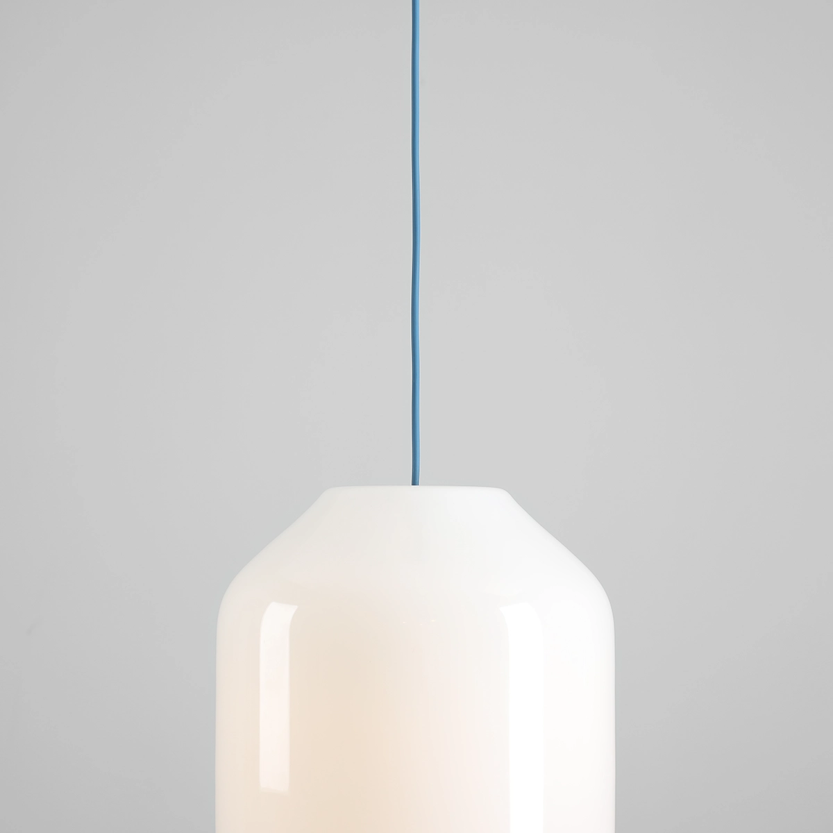 Lampa wisząca Flask Sapphire D27 w kształcie stożka, z białym, błyszczącym kloszem i niebieskim przewodem. Zawieszona na szarym tle, przeznaczona do jednego źródła światła E27.