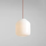 Lampa wisząca Flask Terra D27 w kształcie cylindrycznego klosza, wykonana z białego szkła. Wisi na czerwonym kablu. Prosty, nowoczesny design, idealna do różnych wnętrz. Widoczna oprawka na żarówkę E27. Tło w odcieniu szarości.