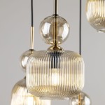 Lampa wisząca Sophia z sześcioma oprawami E14, wykonana z bursztynowego, żebrowanego szkła. Zawiera okrągłe, przezroczyste elementy i złote detale. Wisi na czarnym kablu, tworząc elegancki akcent w aranżacji wnętrza.