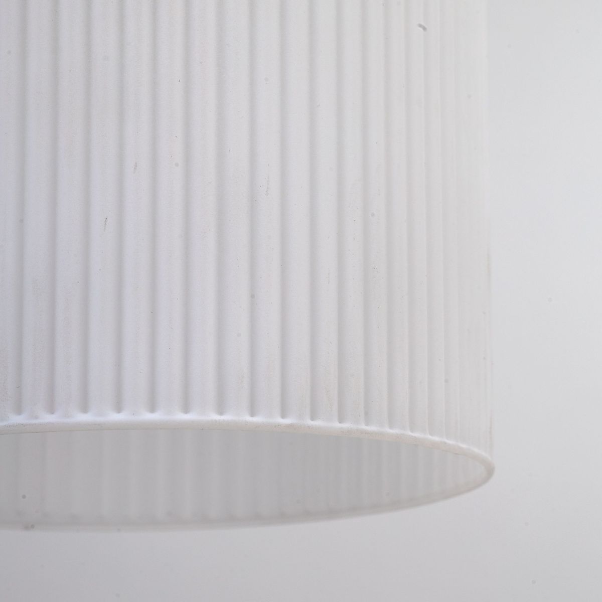 Lampa wisząca Sophia z kloszem w kolorze białym, wykonanym z teksturowanego materiału z pionowymi żłobieniami. Klosz w kształcie cylindrycznym, widoczny z dołu, przeznaczony na jedną żarówkę E14. Prosta forma, idealna do nowoczesnych wnętrz.
