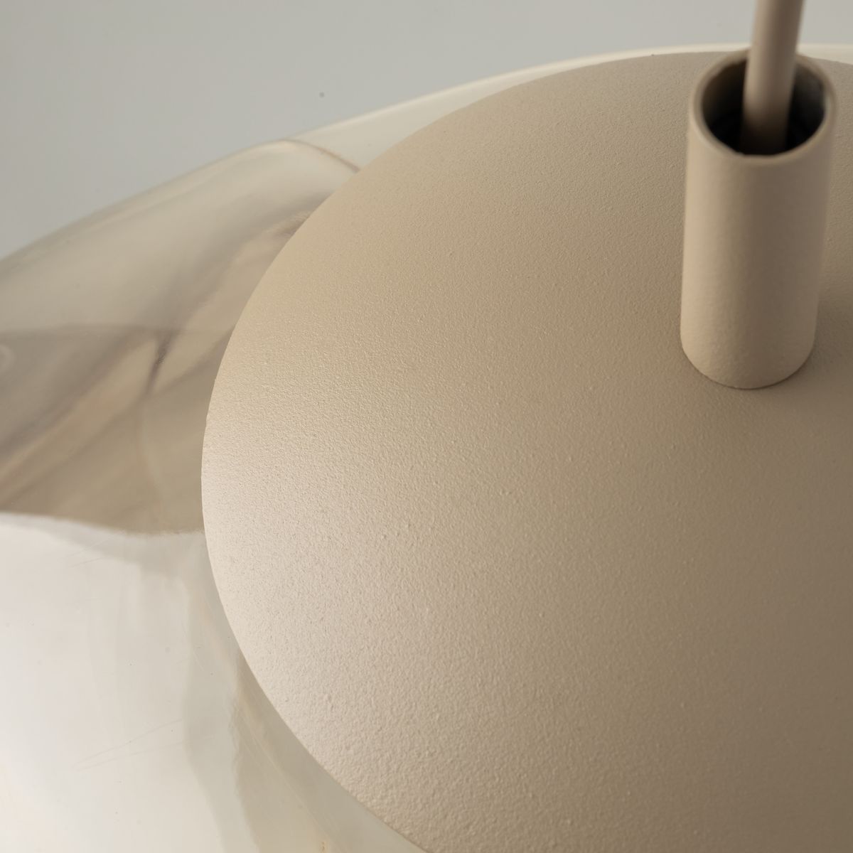Beżowa lampa wisząca Lava Sabia D35 z oprawą E27. Widoczny detal podstawy o matowej fakturze oraz metalowy uchwyt. Kąt ujęcia z góry, ukazujący połączenie lampy z sufitem.