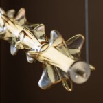 Lampa wisząca LED Elva 30W w kolorze mosiądzu z bursztynowymi kloszami, o dekoracyjnym kształcie gwiazdy. Widok zbliżony, ukazujący detale kloszy oraz metalową podstawę mocującą.