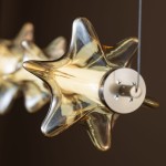 Lampa wisząca LED Elva 30W, kolor mosiężny z bursztynowym kloszem w kształcie gwiazdy. Widok z góry na detal montażowy i fakturę szkła. Idealna do nowoczesnych wnętrz.