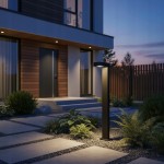 Lampa stojąca ogrodowa Hebin H60, czarna, z wbudowanym gwintem GX53. Produkt widoczny z boku, umieszczony na ścieżce z płyt betonowych, otoczony roślinnością. Tło w zmierzchu, z elewacją budynku w stylu nowoczesnym.