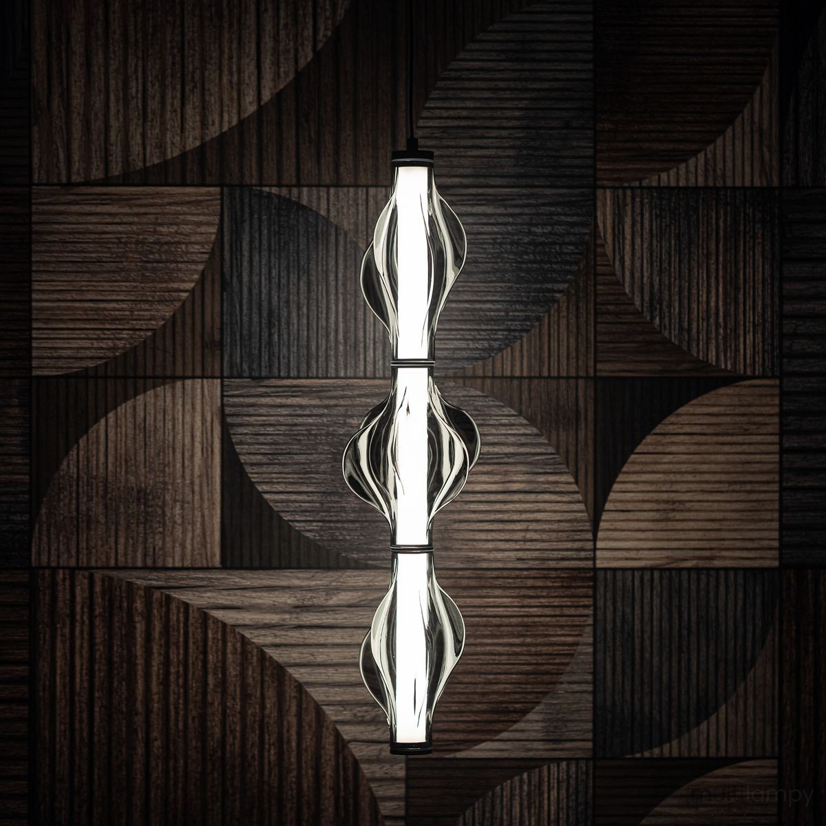 Lampa wisząca LED Elva 22W 3000K w kolorze czarnym/grafitowym, z trzech przeszklonych elementów o falistym kształcie. Zawieszona na minimalistycznym stelażu, w otoczeniu drewnianej, geometrycznej ściany.