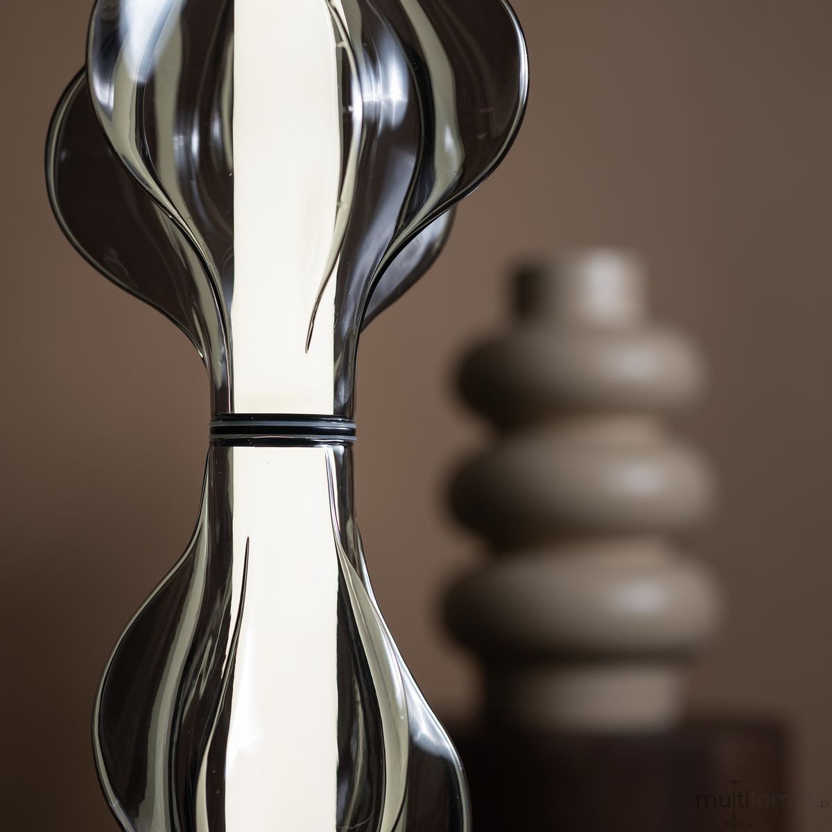 Lampa wisząca LED Elva 22W 3000K w kolorze czarnym i grafitowym. Kształt przypominający falę, z przezroczystymi elementami. Produkt prezentowany na tle neutralnym, w pobliżu ceramicznej dekoracji w odcieniach beżu.