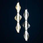 Lampa wisząca LED Elva 22W 3000K w kolorze czarnym i grafitowym. Wyposażona w dekoracyjne, szklane klosze o falistym kształcie, zawieszona na cienkich linkach. Widok z przodu na dwa klosze, jeden z ciepłym światłem, drugi z neutralnym.