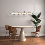 Lampa wisząca LED Elva 30W 3000K w kolorze czarnym/grafitowym, z sześcioma szklanymi kloszami w kształcie kropli, zawieszona nad okrągłym stołem. W tle widoczne krzesła z designerskim siedziskiem i roślina doniczkowa.