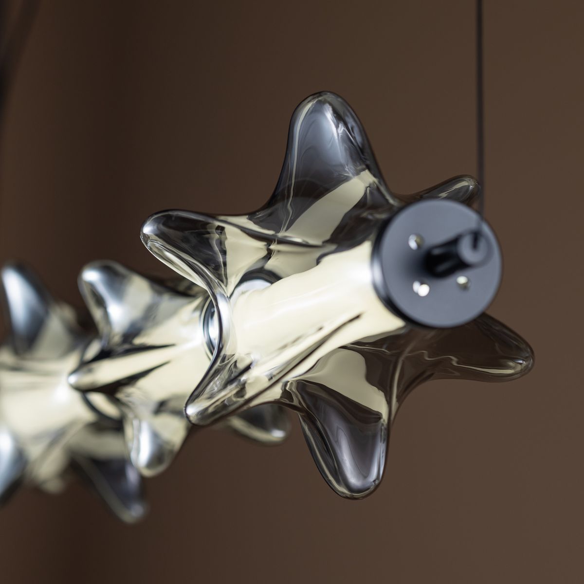 Lampa wisząca LED Elva 30W 3000K w kolorze czarnym/grafitowym. Stylowy, transparentny klosz o formie gwiazdy, zawieszony na cienkim przewodzie. Widoczna metalowa podstawa z mocowaniem. Idealna do nowoczesnych wnętrz.
