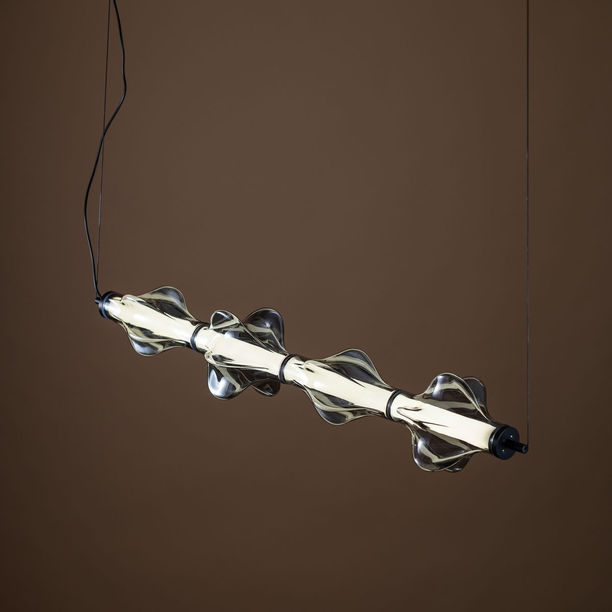 Lampa wisząca LED Elva 30W w kolorze czarnym i grafitowym. Składa się z prostokątnego klosza z falistymi detalami oraz jasnym źródłem światła. Zawieszona na cienkim przewodzie, z widocznym mocowaniem. Idealna do nowoczesnych wnętrz.