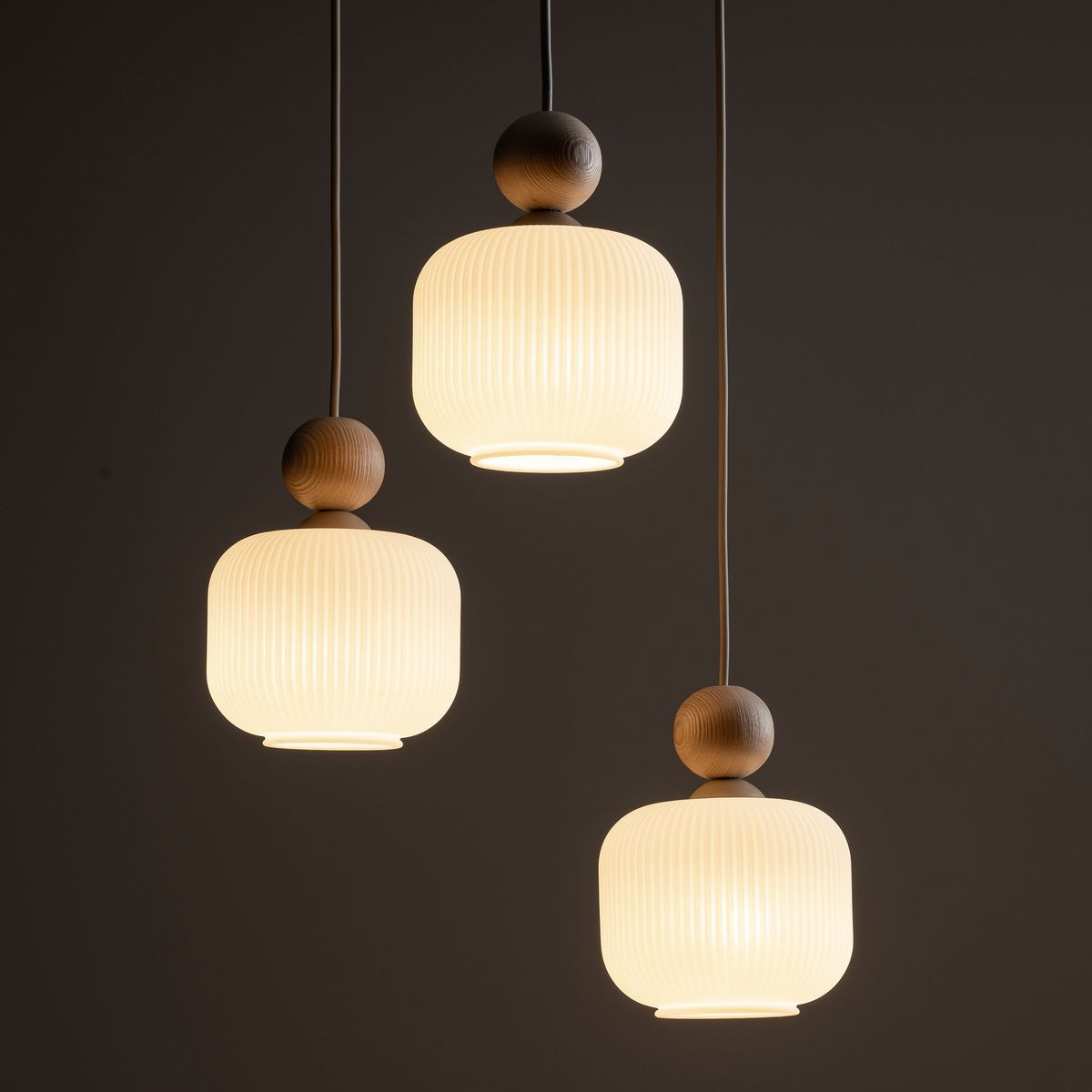 Ballo lampa wisząca z trzema kloszami E14 w beżowym kolorze, z wykończeniem w stylu skandynawskim. Klosze mają żłobienia, a u góry znajdują się drewniane elementy. Lampa zawieszona na cienkich linkach, prezentuje się w nowoczesnym, minimalistycznym stylu.