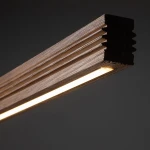 Czarna lampa sufitowa LED Viga Wood o mocy 14W z ciepłym światłem 3000K, wykonana z drewna orzechowego. Widoczny detal: prostokątny, teksturowany korpus z wbudowanym źródłem światła, w zbliżeniu na krawędź lampy.