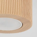 Lampa sufitowa Eve Corte 1xGU10 w kolorze naturalnego buku, z wyraźnym żłobieniem na obudowie. Okrągłe, mleczne szkło osłania źródło światła, w całości widoczna z bliska, zmontowana, z delikatnym, teksturowanym wykończeniem.