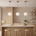 Beżowa lampa wisząca Sphere z opalowym kloszem, zawieszona na długim kablu. Widoczna w nowoczesnej kuchni, nad blatem z jasnego kamienia, w otoczeniu drewnianych stołków. Tło w neutralnych kolorach, minimalistyczne aranżacje.