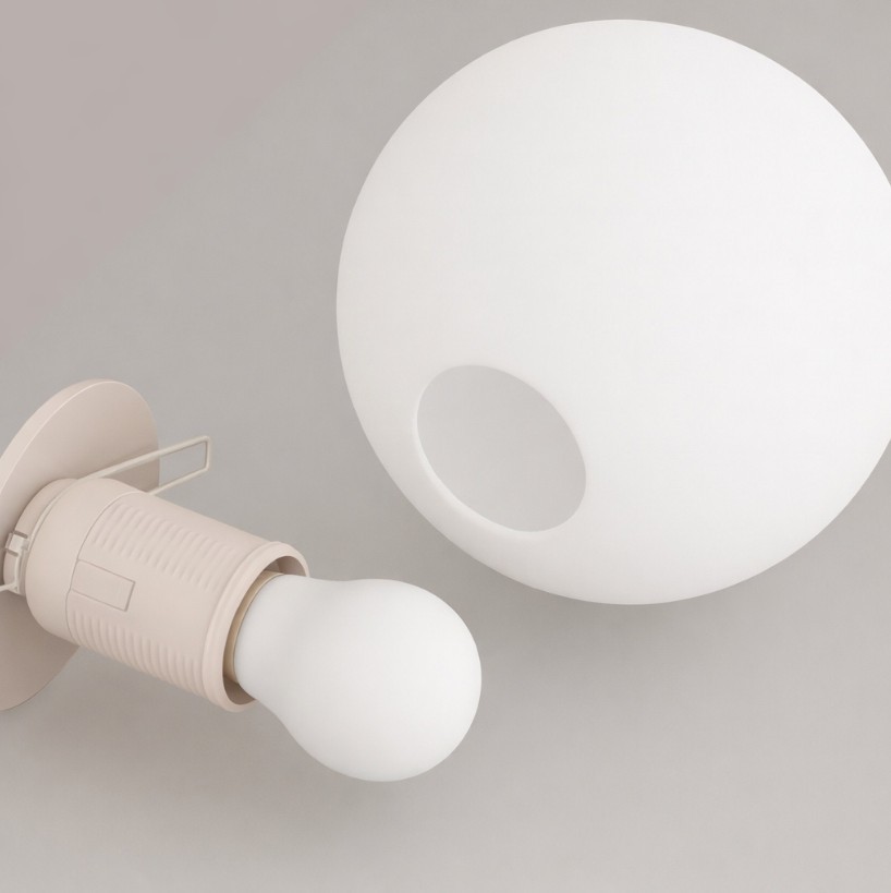 Beżowa lampa wisząca Sphere z jednym źródłem światła E27. Kula o matowej, białej powierzchni i otworem, zawieszona na eleganckim, beżowym uchwycie. Widok z boku, zbliżenie na detal lampy.