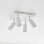 Lampa sufitowa Spoti SQ w kolorze białym z czterema ruchomymi reflektorami na prostokątnej podstawie. Ujęcie z dołu, pokazujące wszystkie cztery klosze o cylindrycznym kształcie, zamontowane na suficie.