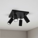 Czarna sufitowa lampa typu spot z czterema reflektorami GU10, zamontowana na kwadratowej płycie. Reflektory mają cylindryczny kształt, skierowane w różnych kierunkach, co pozwala na regulację oświetlenia w pomieszczeniu.