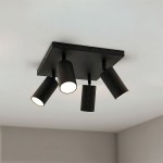 Czarna lampa sufitowa Spoti SQ z czterema ruchomymi reflektorami na kwadratowej podstawie. Reflektory mają cylindryczny kształt, emitują ciepłe światło, zamontowane na suficie w pomieszczeniu. Tło w jasnym kolorze.
