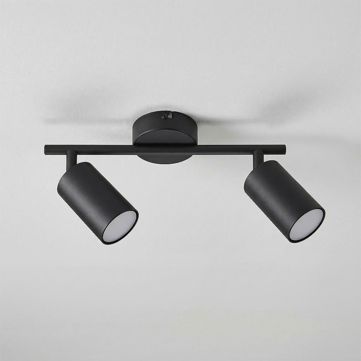 Lampa sufitowa Stico z dwoma reflektorami na ruchomej belce, wykonana w czarnym metalu. Reflektory mają cylindryczny kształt z białymi kloszami. Montowana na suficie, idealna do oświetlenia wnętrz.