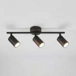Czarna lampa sufitowa typu spot z trzema ruchomymi reflektorami na metalowej ramie. Reflektory mają cylindryczny kształt, emitują ciepłe światło. Umożliwia kierunkowe oświetlenie, zamontowana na okrągłej podstawie. Idealna do nowoczesnych wnętrz.