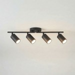 Czarna lampa sufitowa Stico z czterema reflektorami GU10, umieszczona na prostokątnej podstawie. Reflektory mają cylindryczny kształt, są ustawione w różnych kierunkach, co umożliwia skierowanie światła w pożądane miejsca. Tło jasne.