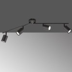 Czarna lampa sufitowa Stico z czterema reflektorami GU10, zamontowana na prostym stelażu. Reflektory są cylindryczne, skierowane w różnych kierunkach, co umożliwia regulację oświetlenia. Tło w szaro-białym odcieniu podkreśla minimalistyczny design.