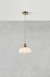 Lampa wisząca Kurage E27 w kolorze antycznego mosiądzu z białym kloszem w kształcie kwiatowym. Zawieszona na cienkim przewodzie, z montażem sufitowym. Tło w odcieniu szarym, minimalistyczne.