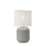 Lampa stołowa Montagna z szarym, teksturowanym kloszem i białym abażurem. Ustawiona w pozycji stojącej, z okrągłym, lekko zaokrąglonym korpusem. Klosz z materiału o lekko przezroczystej strukturze, emitujący miękkie światło.