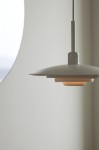 Lampa wisząca E27 w kolorze białym, o nowoczesnym kształcie. Zawieszona na cienkim kablu, z okrągłym kloszem, który ma wycięcia. Tło jasne, gładkie, co podkreśla minimalistyczny design lampy.