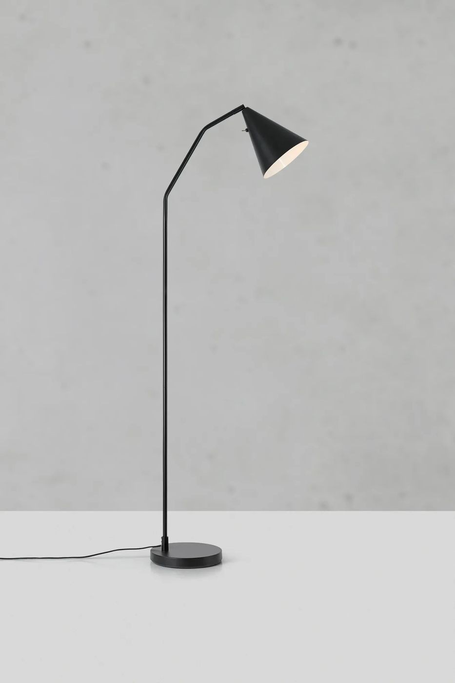 Czarna lampa podłogowa LED Funil 4,9W z metalowym kloszem w kształcie stożka i prostą, smukłą nogą. Ujęcie z boku, na białym tle, z widoczną okrągłą podstawą i przewodem zasilającym.