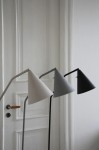 Lampa podłogowa LED Funil 4,9W w kolorze czarnym, z metalowym kloszem w kształcie stożka. Ujęcie z boku, w grupie z lampami w odcieniach bieli i szarości. Stojąca, minimalistyczna konstrukcja na prostym tle.