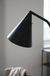 Czarna lampa podłogowa LED Funil o mocy 4,9W, z charakterystycznym stożkowym kloszem, z bliska ukazuje gładką, matową powierzchnię oraz ruchomy ramion, umieszczona w minimalistycznym wnętrzu.