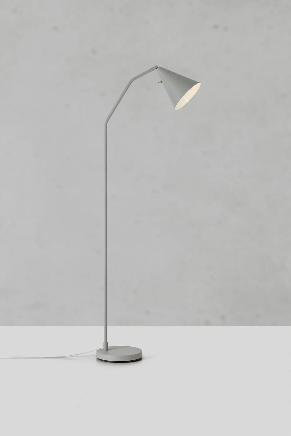 Lampa podłogowa LED Funil 4,9W w kolorze szarym, o minimalistycznym designie. Posiada stożkowy klosz i smukłą, metalową nogę. Ujęcie z boku, na jednolitym tle. Stabilna, okrągła podstawa zapewnia solidność.