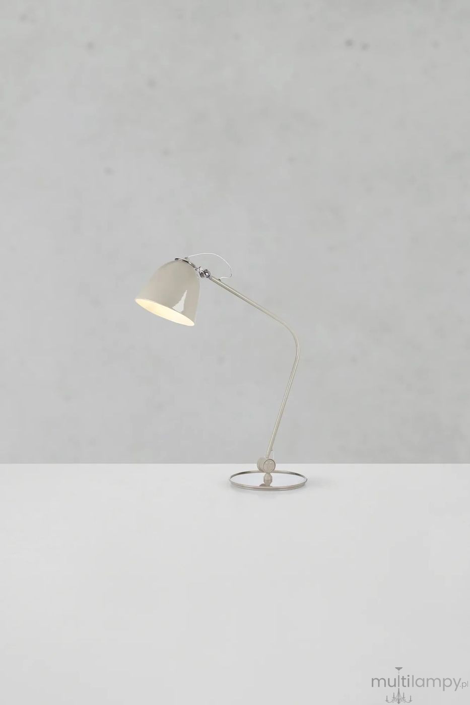 Lampa stołowa Tilt E27 w szarym kolorze z metalowym kloszem i elastycznym ramieniem. Ustawiona na okrągłej podstawie, skierowana w górę. Tło w jasnym odcieniu, podkreślającym prosty design. Idealna do biura lub na stół.