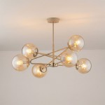 Lampa wisząca Sagito 6xE14 w kolorze beżowym z metalowymi elementami w złotym odcieniu. Posiada sześć przezroczystych kulistych kloszy, zamontowana na długim, prostym stelażu. Widok z dołu, na jasnym tle.