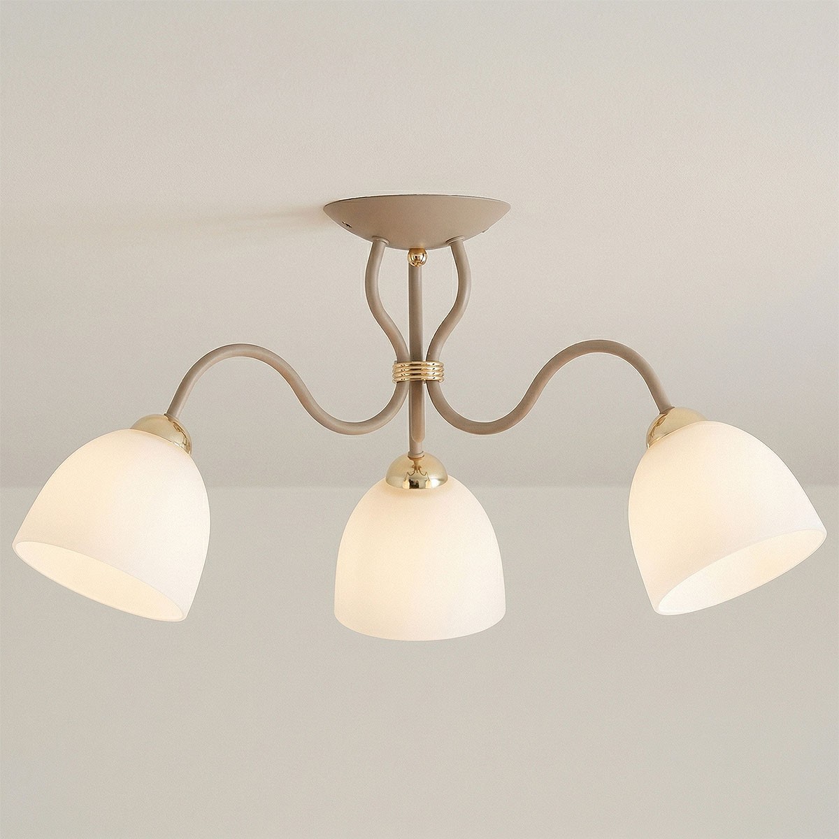 Lampa sufitowa Ariel w kolorze taupe z trzema kloszami z białego szkła, zawieszona na złotym stelażu. Ujęcie z dołu, pokazujące kształt kloszy i detale montażowe. Idealna do nowoczesnych wnętrz.