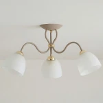 Lampa sufitowa Ariel z trzema kloszami E27 w kolorze taupe i złotej metalowej oprawie. Klosze mają zaokrąglony kształt i matowe wykończenie, a całość zamontowana jest na stelażu z falistymi ramionami.