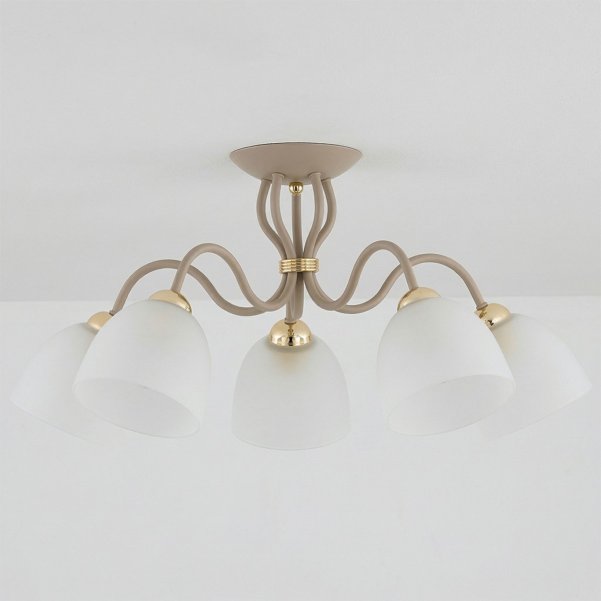 Lampa sufitowa Ariel w kolorze taupe z pięcioma kloszami w kształcie półkul, wykonanymi z matowego szkła. Elementy wykończeniowe w kolorze złotym. Produkt zamontowany na suficie, z widocznymi lekko falującymi ramionami.