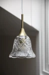 Lampa wisząca Luna E14 w kolorze antycznego mosiądzu, z przezroczystym kloszem o lekko falującym kształcie, zdobionym diamentowym wzorem. Zawieszona na białym przewodzie, w widoku z przodu, idealna do nowoczesnych wnętrz.