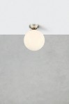 Lampa sufitowa Stintino z oprawą w kolorze niklu satynowego. Okrągła, mleczna kula z tworzywa, zamontowana na suficie. Prosty design, idealna do nowoczesnych wnętrz. Tło w odcieniach szarości.