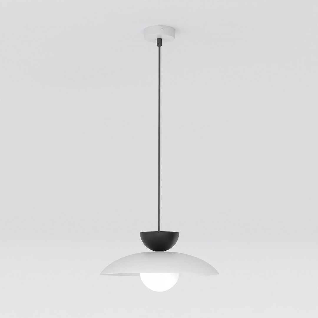 Lampa wisząca Mulan z jedną oprawą G9 w kolorze szarym i czarnym. Okrągła, matowa czasza z białym wykończeniem, zawieszona na cienkim, czarnym przewodzie, montowana do sufitu. Prosty, nowoczesny design na jasnym tle.