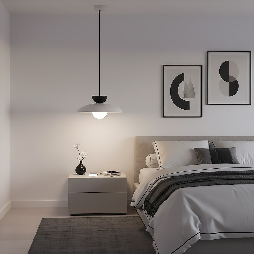 Lampa wisząca Mulan w kolorze szarym i czarnym, z jednym źródłem światła G9. Zawieszona na cienkim kabelku, z okrągłą, białą osłoną nad żarówką i czarnym kloszem. Widoczna w nowoczesnej sypialni, w pobliżu łóżka i stolika nocnego.