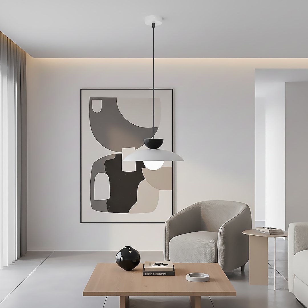 Lampa wisząca Mulan w kolorze szarym i czarnym, z jedną oprawą G9, zawieszona na cienkim przewodzie. Umieszczona w nowoczesnym wnętrzu z abstrakcyjnym obrazem, obok wygodnych foteli i drewnianego stolika. Tło jasne, minimalistyczne.