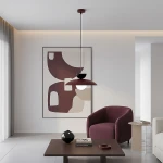 Lampa wisząca Mulan 1xG9 w kolorze burgundowym z czarnym kloszem, zawieszona na cienkim przewodzie. W tle widoczny nowoczesny obraz na ścianie, a w aranżacji meble w kolorach burgundu i beżu, stół z dekoracjami.