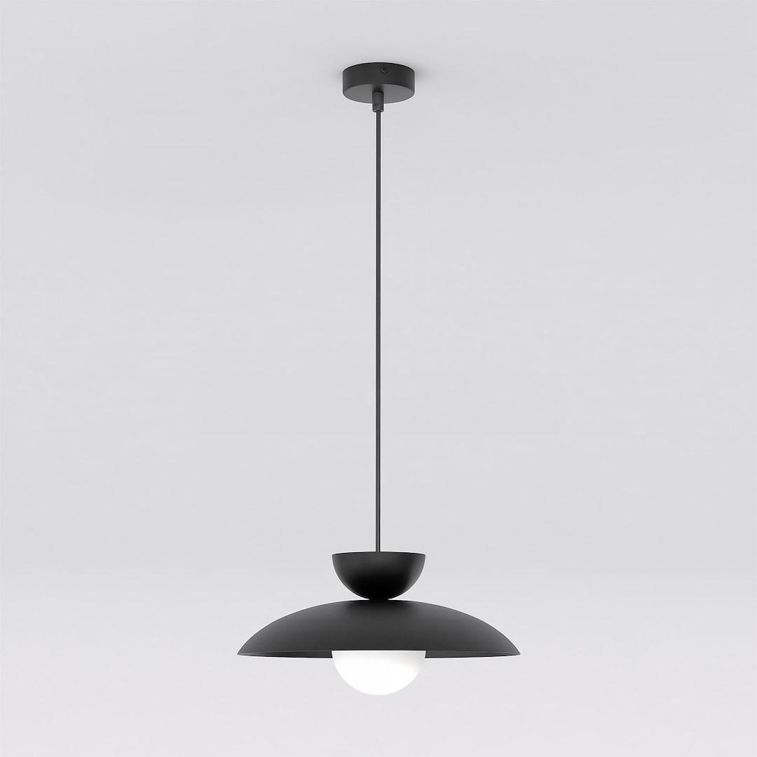 Lampa wisząca Mulan w kolorze czarnym, z jedną oprawą G9. Posiada okrągły, białą kulę w dolnej części oraz półkulisty klosz u góry. Wisi na cienkim przewodzie w prostym, minimalistycznym stylu. Tło białe, co podkreśla elegancki design.
