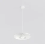Biała lampa wisząca o okrągłej, płaskiej podstawie z centralnym, stożkowym elementem. Zawieszona na cienkim, białym przewodzie. Tło w jasnym kolorze, podkreślające minimalistyczny design.