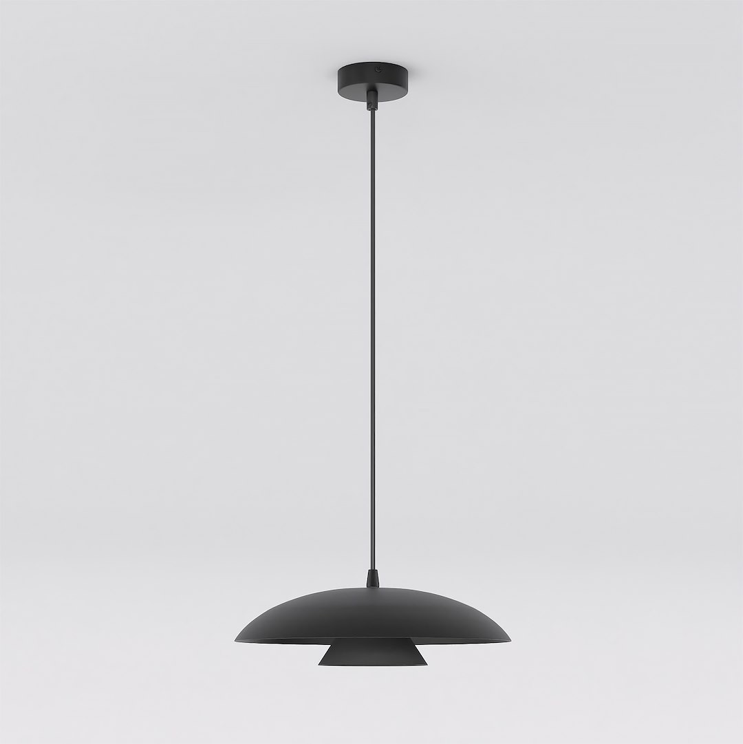Czarna lampa wisząca Babel z jedną oprawą GX53, o zaokrąglonym kształcie i matowej powierzchni. Zawieszona na cienkim przewodzie, z okrągłym mocowaniem sufitowym, idealna do nowoczesnych wnętrz.