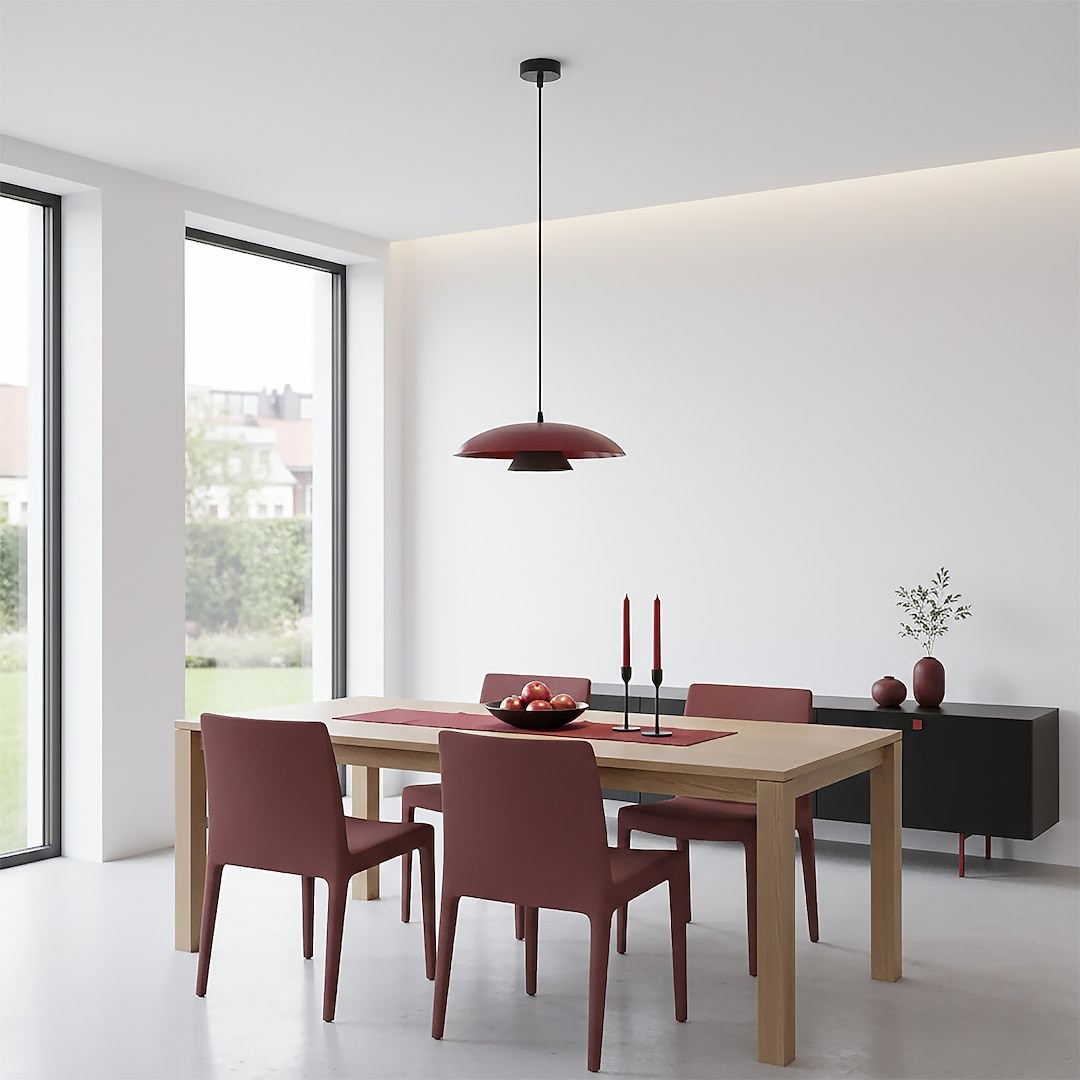 Lampa wisząca Babel w kolorze czarnym i burgundowym, z pojedynczym źródłem światła GX53, zawieszona nisko nad drewnianym stołem w nowoczesnej jadalni. W tle widoczne burgundowe krzesła, czarne meble i naturalne światło wpadające przez okna.
