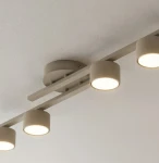 Fragment lampy sufitowej 4xGX53 w kolorze mokka, z metalową konstrukcją i okrągłymi kloszami. Ujęcie z góry, ukazujące zamontowane na suficie źródła światła. Klosze mają jasne, emitujące światło wnętrze, utrzymane w minimalistycznym stylu.